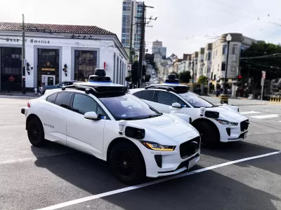 Two white Waymo robotaxis parked on street in San Francisco, California.